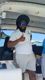 A crew member on a boat gives a thumbs up, showcasing a friendly atmosphere on board — perfect for a fun day out on the water.