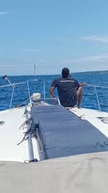 A person enjoys a moment of relaxation on the bow of a boat, surrounded by the serene blue ocean — perfect for a day of cruising and unwinding.