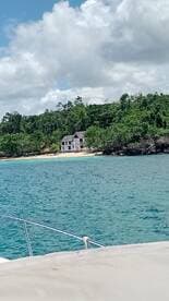 A picturesque view of a secluded beach with a charming house nestled among lush greenery, perfect for showcasing serene coastal destinations.