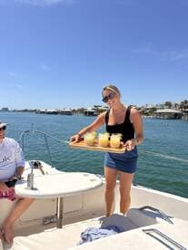 A cheerful woman serves refreshing cocktails on a sunny day aboard a boat, perfect for enjoying time with friends and celebrating special moments on the water.
