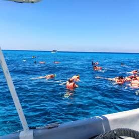 A lively group enjoys snorkeling in the vibrant blue waters, showcasing the excitement of underwater exploration and adventure.
