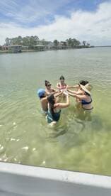 A lively group of friends enjoys a fun moment in the water, celebrating together in a picturesque setting — perfect for summer gatherings and memorable outings.