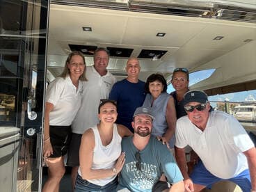 A cheerful group poses together inside a luxurious boat, capturing a moment of celebration and camaraderie on the water.