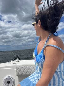 A woman joyfully waves her hand while enjoying a day on the water, capturing the essence of fun and adventure aboard a boat.
