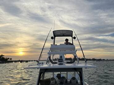 A person navigates a boat during a stunning sunset, capturing the essence of a perfect evening on the water.