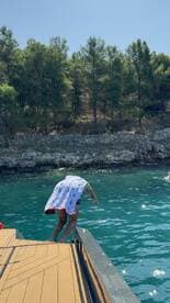 A person prepares to jump into the crystal-clear waters, capturing the excitement of a summer day on the boat — perfect for swimming and water activities.
