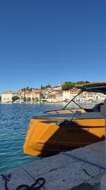 A striking view of a docked boat with a vibrant orange hull, set against a picturesque coastal town, perfect for showcasing boating adventures in scenic locations.
