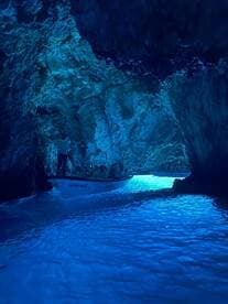 A group of adventurers explores a stunning cave by boat, surrounded by mesmerizing blue waters — a perfect highlight of a unique tour experience.