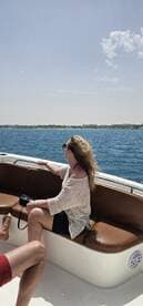 A woman enjoys the ocean breeze while seated on a boat, capturing the moment with her camera — a perfect snapshot of a sunny day on the water.