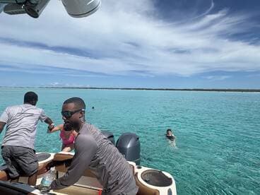 A lively scene captures guests enjoying a refreshing swim in crystal-clear turquoise waters, with a boat in the foreground — perfect for a fun day on the water.