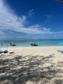 A picturesque beach scene featuring two boats anchored in turquoise waters, perfect for a relaxing day by the shore.