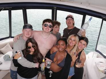 A lively group of friends enjoys a fun moment aboard a boat, celebrating with drinks and laughter — perfect for unforgettable summer outings.