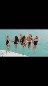 A group of friends joyfully jumps into the turquoise waters from the side of a boat, capturing the essence of summer fun and adventure on the water.