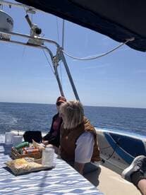 Two friends enjoy snacks and drinks on the deck of a boat, perfect for a relaxing day at sea.