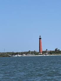 A scenic view of a striking red lighthouse standing tall along the coastline, perfect for capturing the essence of coastal adventures and maritime navigation.