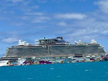 A stunning view of the Norwegian Aqua cruise ship sailing through clear turquoise waters, showcasing its vibrant exterior and modern design.