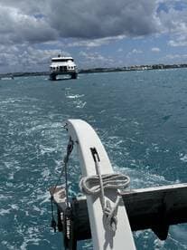 A view from the bow of a boat, showcasing the vessel in motion against a backdrop of turquoise waters and a distant shoreline.