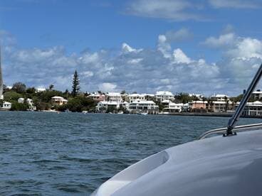 A scenic view of a picturesque coastline with charming homes along the shore, captured from a boat, showcasing the beauty of the waterfront.