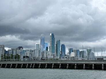 A cloudy view of a city skyline with waterfront structures, capturing the essence of urban life near the water.