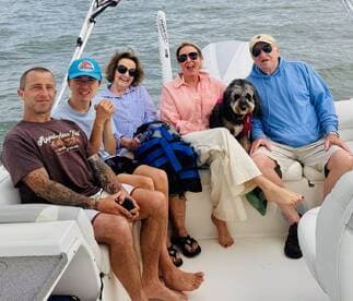 A cheerful group of family and friends relaxes on a boat, enjoying their time together with a dog, perfect for memorable outings on the water.