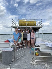 A cheerful group poses together on a pontoon boat, capturing a memorable moment on the water — perfect for celebrations and fun outings.
