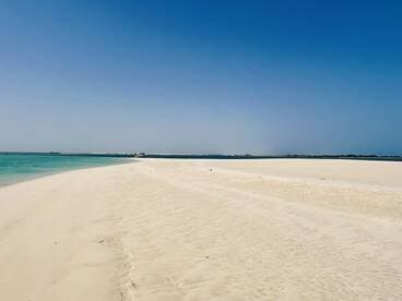 A stunning view of a pristine beach with soft white sand and clear turquoise waters, perfect for a relaxing day by the coast.