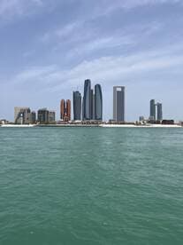 A stunning view of the Abu Dhabi skyline from the water, showcasing modern architecture against a clear blue sky — perfect for sightseeing and city tours.