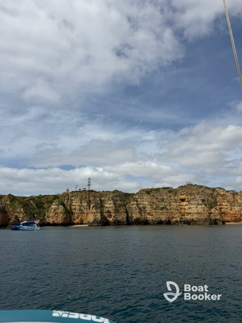 A stunning view of rugged cliffs and a boat anchored near the coastline, showcasing the natural beauty of the area — perfect for sightseeing and exploration.