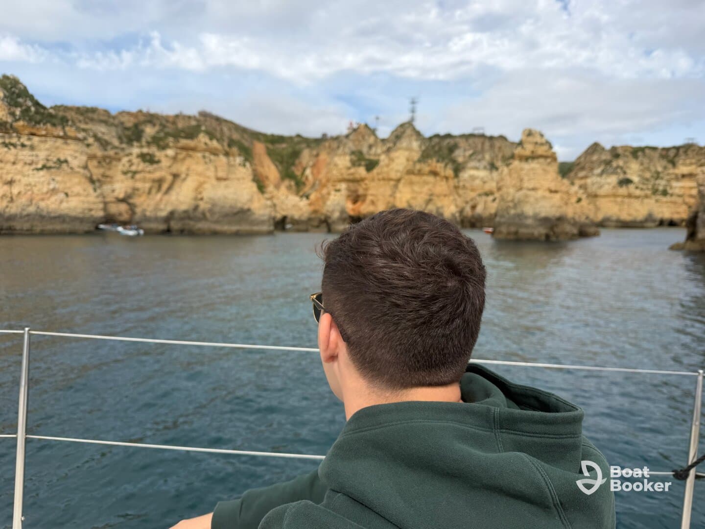 A guest enjoys the stunning coastal views while aboard a boat, showcasing the beautiful rock formations and serene waters — perfect for exploration and sightseeing.