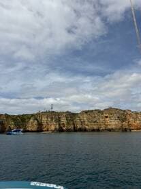 A stunning view of rugged cliffs and a boat anchored near the coastline, showcasing the natural beauty of the area — perfect for sightseeing and exploration.
