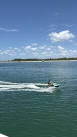 A thrilling moment captured as a rider enjoys jet skiing in clear waters, with a picturesque beach backdrop — perfect for adventure seekers on their water excursions.