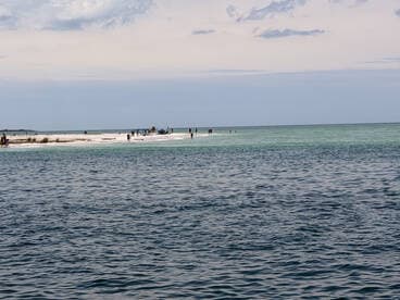 A vibrant scene at a sandbar with people enjoying the beach and shallow waters, perfect for a fun day out on the water.