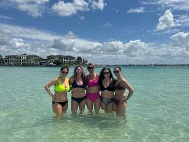 A group of friends enjoys a sunny day at the beach, wading in the clear waters and celebrating together — perfect for summer fun and memorable outings.