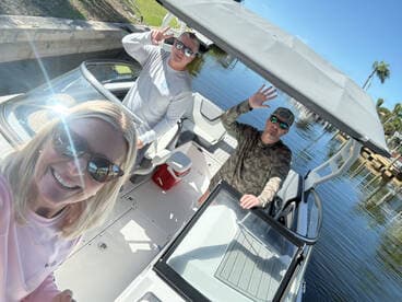 A cheerful group enjoys a sunny day on the boat, capturing a fun selfie while showcasing their excitement for a day on the water.