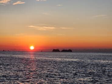 A breathtaking sunset over the ocean, with silhouetted islands in the distance, creating a picturesque scene perfect for romantic evenings or serene boat trips.