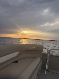 A cozy seating area on a pontoon boat, perfectly positioned to enjoy a stunning sunset over the water.