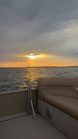 A serene view from the interior of a pontoon boat, showcasing comfortable seating with a stunning sunset over the water — perfect for relaxing cruises.
