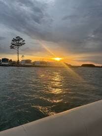 A serene sunset view from a boat, showcasing the shimmering water and distant shoreline, perfect for peaceful evening cruises.