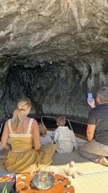 A family enjoys a moment of exploration inside a cave while on a boat, capturing the beauty of their adventure together.