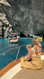 A mother and child enjoy a scenic boat ride near a stunning cave, capturing a memorable family adventure on the water.