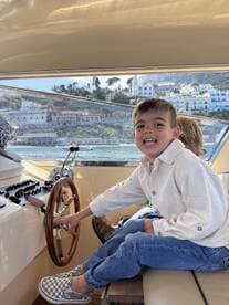 A joyful child interacts with the helm of a boat, showcasing the fun of boating experiences for families. The cozy interior setting highlights the charm of a day on the water.