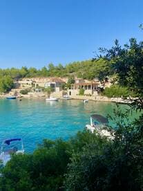 A picturesque view of a serene harbor with crystal-clear waters and lush greenery, perfect for exploring the beautiful coastline.