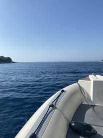 A serene view of a boat navigating through calm waters, showcasing the beauty of the open sea and surrounding landscape.