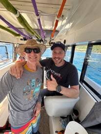 Two friends enjoy a moment inside the boat's cabin, showcasing the comfortable seating and helm area, perfect for a day on the water.