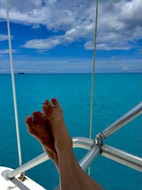 A serene view of feet resting on the railing of a boat, overlooking the stunning turquoise ocean — a perfect moment of relaxation on the water.