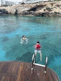 Two individuals enjoy a refreshing swim in crystal-clear waters, showcasing a fun and relaxing day on the water.