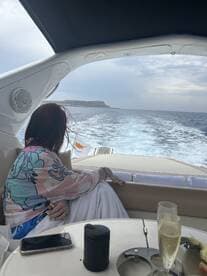 A guest enjoys a relaxing moment on the boat, gazing at the scenic coastline while sipping champagne — perfect for a luxurious day on the water.