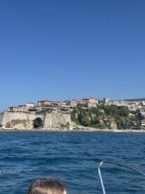 A scenic view of a coastal town from a boat, showcasing beautiful architecture and clear blue waters — perfect for exploring picturesque destinations.