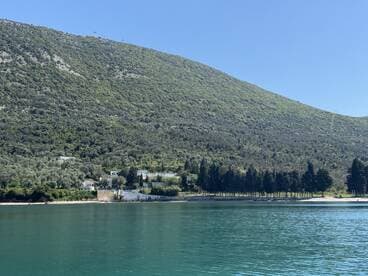 A stunning view of lush green mountains reflecting in tranquil waters, showcasing the natural beauty of the coastline — perfect for nature lovers and scenic boat trips.