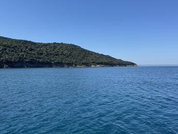 A serene view of a lush coastline meeting tranquil blue waters, perfect for showcasing the natural beauty of the area.